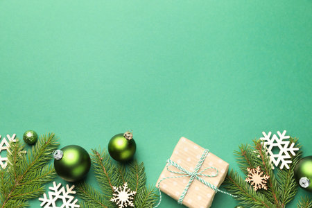 Beautiful Christmas composition with gift and decor on green background, flat lay. Space for text