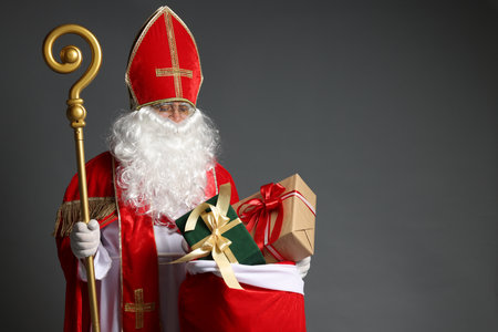 Saint Nicholas with crozier and sack full of gifts on gray background. Space for textの写真素材