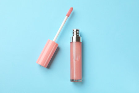 Beautiful lip gloss with applicator on light blue background, top viewの写真素材