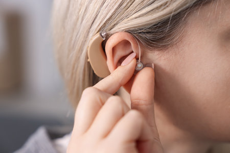 Woman with hearing aid at home, closeup. Space for text