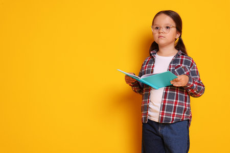 Cute little girl with book on background, space for textの写真素材