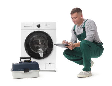 Repairman in uniform with pen, clipboard, toolbox and washing machine on white backgroundの写真素材
