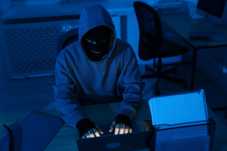 Thief hacking system with laptop in office at nightの写真素材