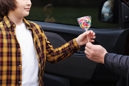 Stranger in car giving lollipop to little boy, closeup.の写真素材