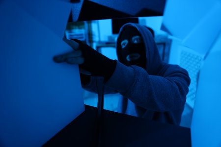 Thief in mask looking for money in office at night