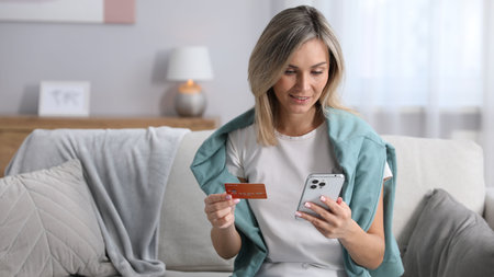 Woman making online payment with phone and credit card indoors, space for text