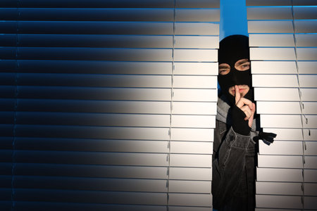 Thief breaking into house through window at nightの写真素材