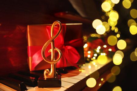 Christmas atmosphere. Golden treble clef and gift box on piano against black background, closeup with space for text. Bokeh effectの写真素材