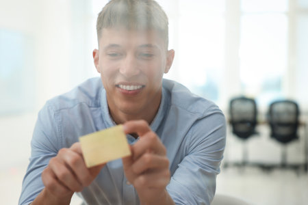 Man sticking note on glass board in officeの写真素材