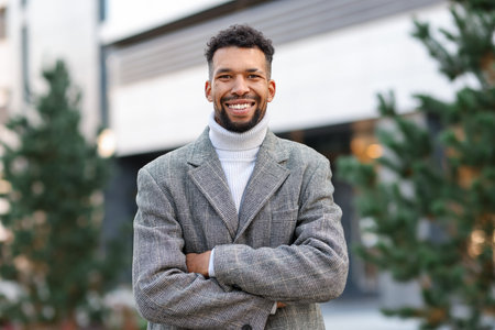 Portrait of smiling man in suit with crossed arms on city streetの写真素材