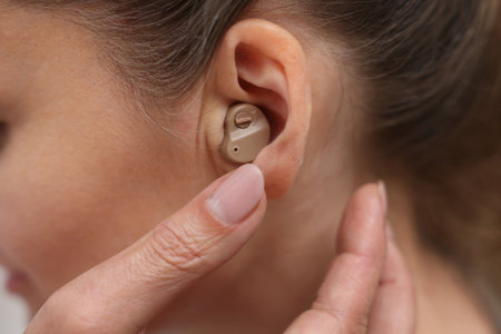 Doctor putting hearing aid into patient's ear, closeup