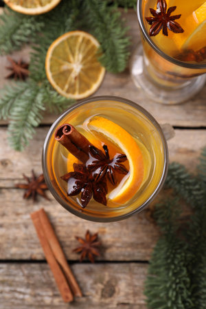 Delicious mulled white wine with slices of orange, spices and fir branches on wooden table, flat layの写真素材