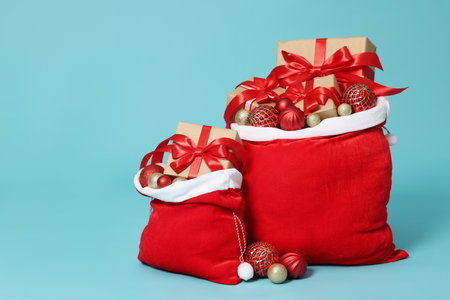 Santa Claus bags with Christmas gifts and balls on light blue background, space for textの写真素材