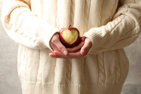 Woman holding ripe apple with carved heart, closeupの写真素材