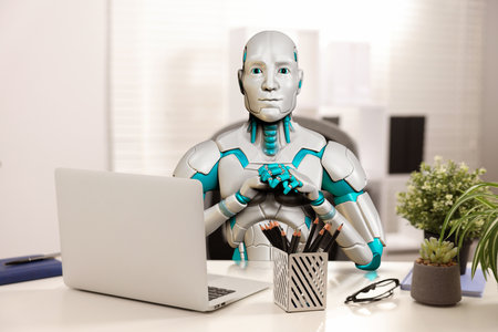 Replacing humans with artificial intelligence. Robot working at table in office. Futuristic technologiesの写真素材