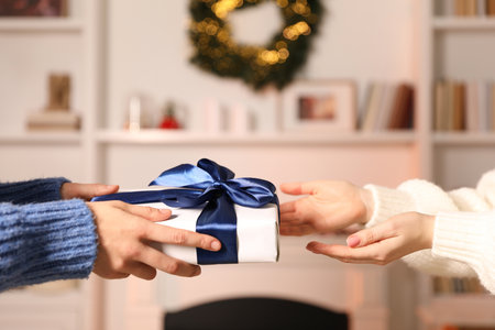 Merry Christmas and Happy New Year. Woman giving gift box to her friend indoors, closeupの写真素材