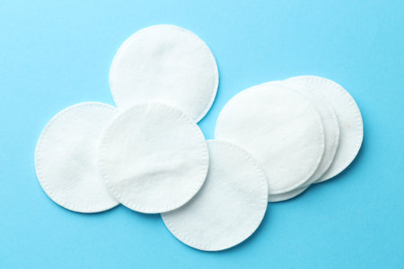 Clean cotton pads on light blue background, flat layの写真素材