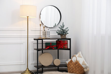 Mirror, burning candles and Christmas decor on console table near white wall indoors. Interior designの写真素材