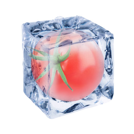 Whole red tomato in ice cube inside isolated on whiteの写真素材