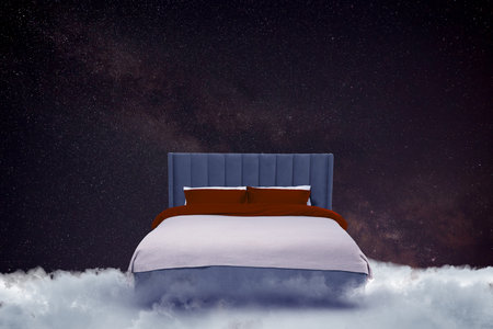 Large bed on fluffy clouds in starry night sky
