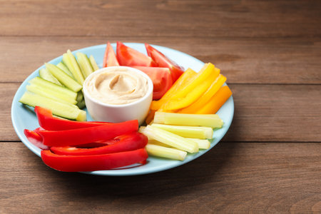 Different fresh vegetables and sauce on wooden table, closeup