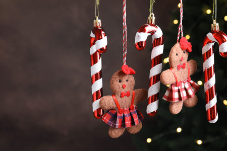 Beautiful Christmas decor hanging against dark gray background with blurred lights, closeup. Space...