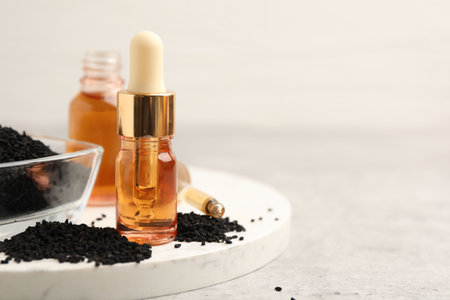 Black cumin seeds and oil on light table, closeup. Space for textの写真素材