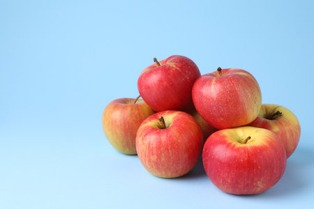 Ripe red apples on light blue background, closeup. Space for textの写真素材