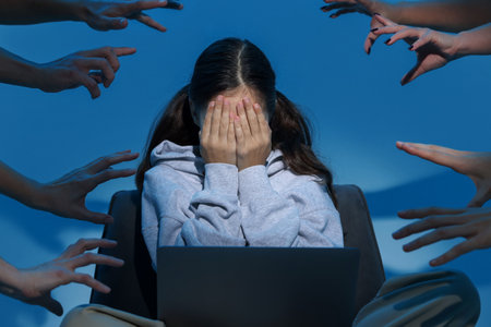 Cyber danger. Frightened girl using laptop while hands reaching towards her on blue backgroundの写真素材