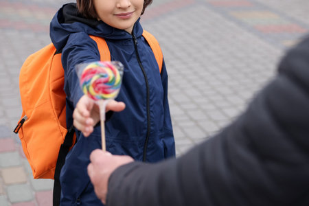 Stranger giving lollipop to little boy outdoors, closeup.の写真素材