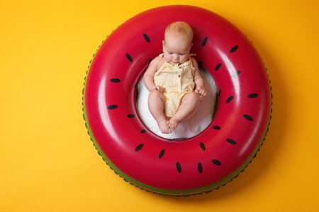 Cute little baby on inflatable ring against orange background, top viewの写真素材
