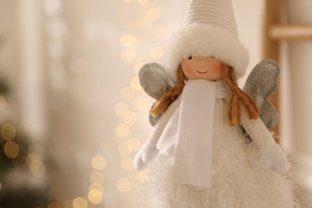 Cute fairy figure against blurred lights indoors, closeup with space for text. Merry Christmas and Happy New Yearの写真素材