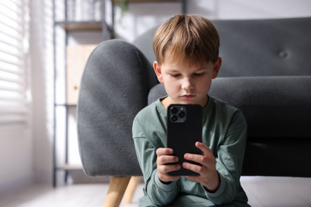 Cyber danger. Little boy using smartphone at home