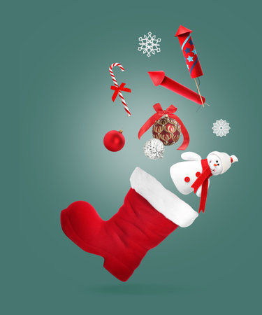 Christmas balls and other decor falling into red boot on teal backgroundの写真素材