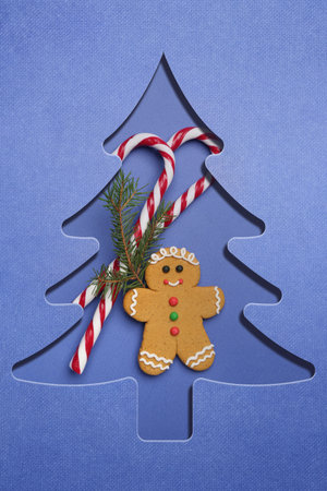 Merry Christmas and Happy New Year! Greeting card with Christmas tree cut in blue paper, gingerbread...