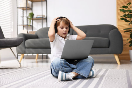Frightened little boy using laptop at home
