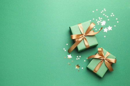 Beautiful Christmas gifts and confetti on green background, flat lay. Space for textの写真素材