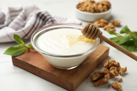 Delicious Greek yogurt with honey and walnuts served on white table, closeupの写真素材