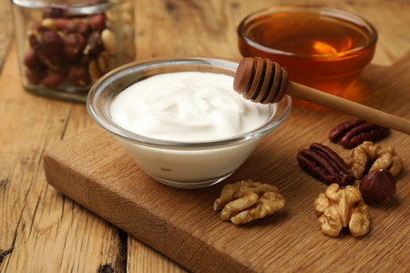 Delicious Greek yogurt with honey and nuts on wooden table, closeupの写真素材