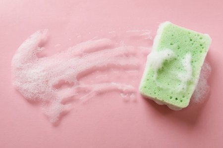 Kitchen sponge with foam on pink background, top viewの写真素材