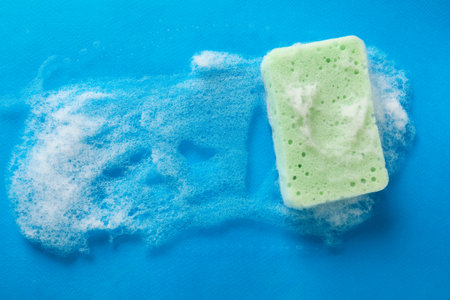 Kitchen sponge with foam on light blue background, top viewの写真素材