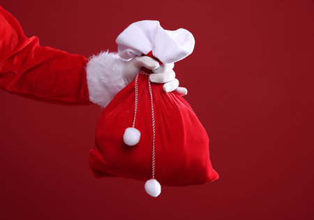 Santa Claus holding sack on red background, closeup. Merry Christmas and Happy New Yearの写真素材