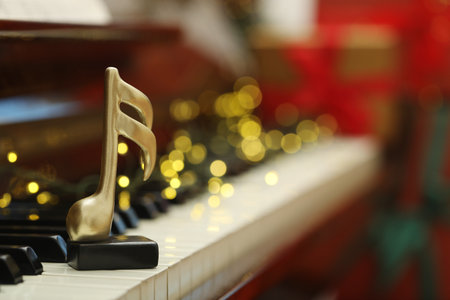 Christmas atmosphere. Golden music note on piano against blurred lights, closeup with space for text. Bokeh effectの写真素材