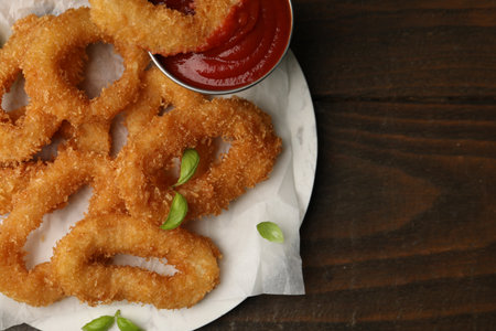 Deep fried squid rings with basil on wooden table, top viewの写真素材