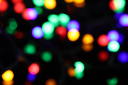 Blurred view of bright Christmas lights on dark background, bokeh effectの写真素材