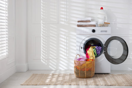 Modern washing machine, detergent and clothes indoors, space for textの写真素材