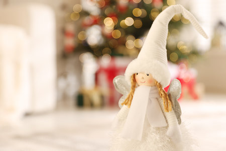 Cute fairy figure against blurred lights indoors, closeup with space for text. Merry Christmas and Happy New Yearの写真素材