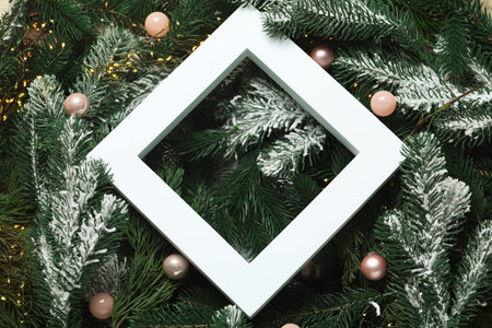 Frame on artificial fir tree branches and Christmas decor, top view. Space for textの写真素材