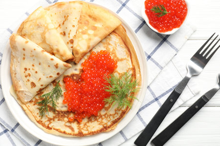 Delicious crepes with red caviar served on white wooden table, flat layの写真素材