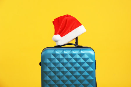 Christmas vacation. Blue suitcase with Santa hat on orange backgroundの写真素材